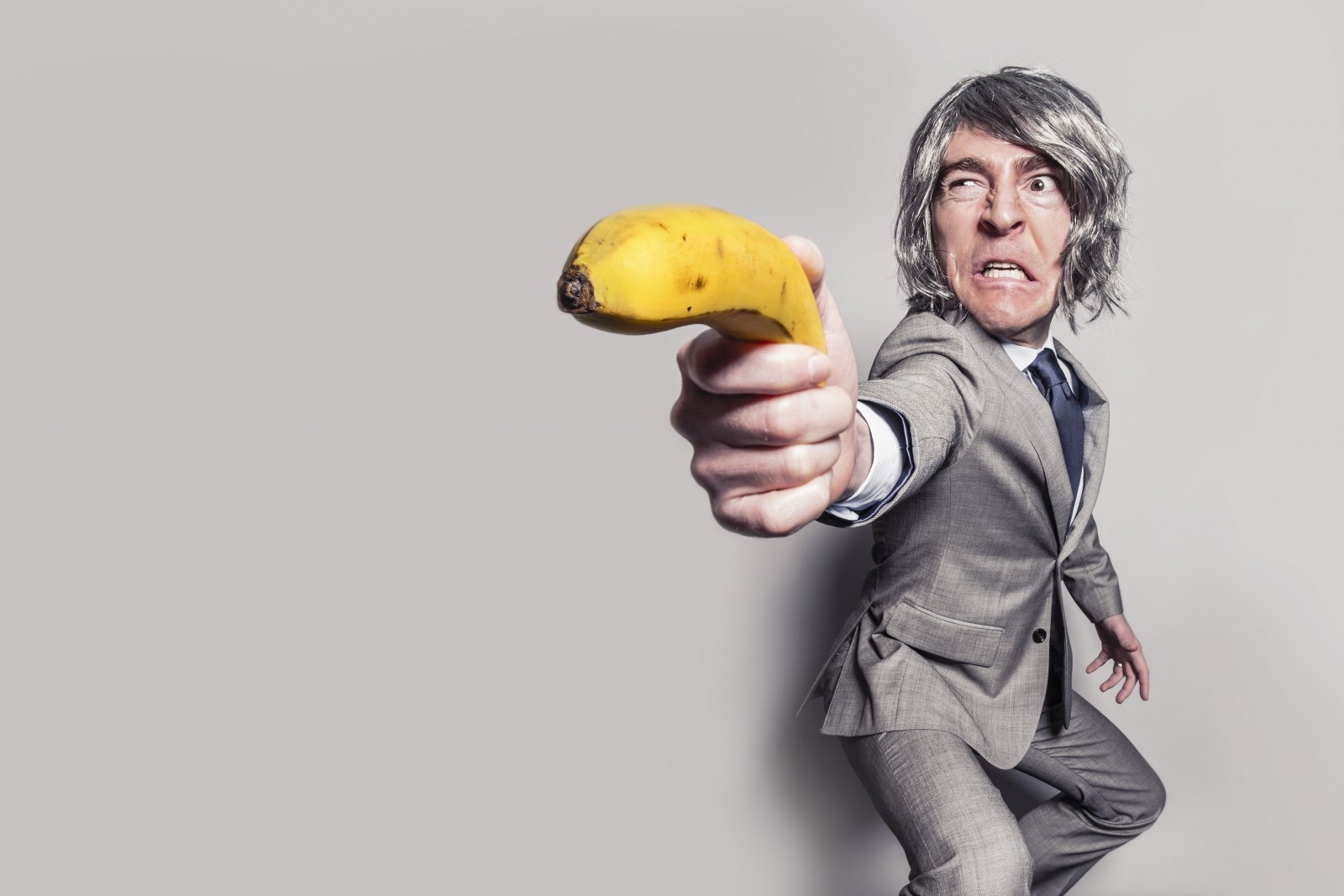 Average look of a business man holding a banana as a weapon