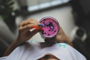A woman holding blueberry smoothie